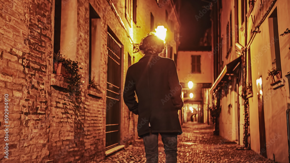 Solitude in the Dark: Young Man Walking Alone in Nighttime City Alleyway