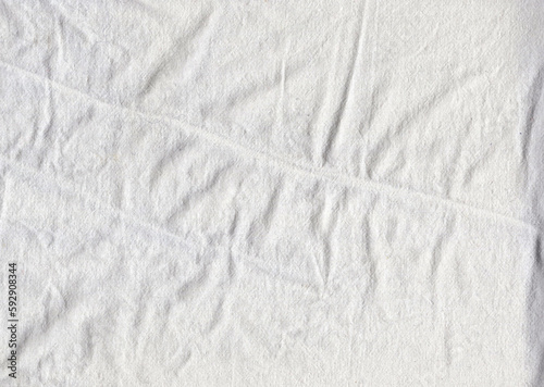 The texture of the cotton fabric of the sheet with slight folds and wrinkles over the entire surface. The folds are arranged in a chaotic order