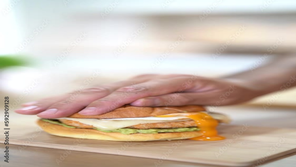 Vertical shot of a chef pressing a burger making the yolk drip on the side Vertical shot of a chef pressing a burger making the yolk drip on the side