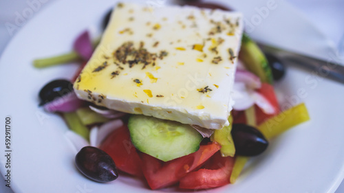 Fototapeta Naklejka Na Ścianę i Meble -  Traditional fresh greek salad with vegetables, feta cheese, spices olives and olive oil on a plate served in traditional Greek cafe tavern restaurant in the street of Athens, Greece