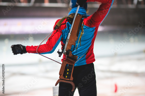 Biathlete with rifle on a shooting range during biathlon training, skiers on training ground in winter snow, athletes participate in biathlon competition on slope piste photo