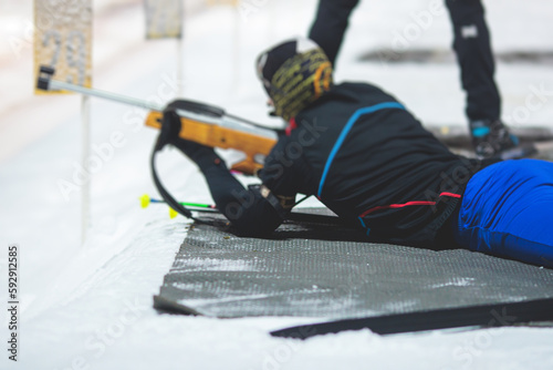 Biathlete with rifle on a shooting range during biathlon training, skiers on training ground in winter snow, athletes participate in biathlon competition on slope piste photo