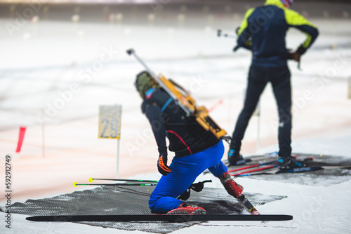 Biathlete with rifle on a shooting range during biathlon training, skiers on training ground in winter snow, athletes participate in biathlon competition on slope piste