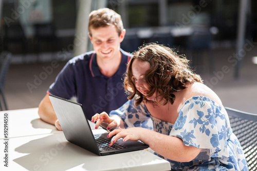 Young person who has down syndrome working with her disability worker NDIS provider on laptop photo