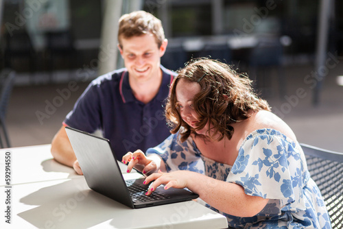 Young person who has down syndrome working with her disability worker NDIS provider on laptop
