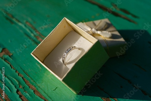 Top view of a box with a beautiful ring in it on a green painted wood
