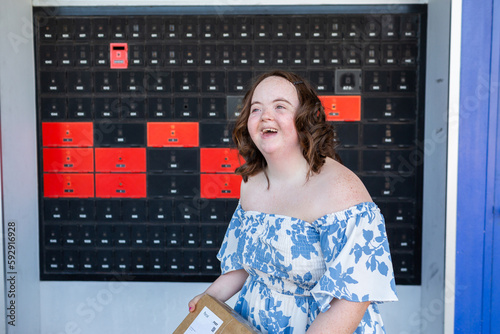 Happy young person with a disability holding brown box parcel near post office