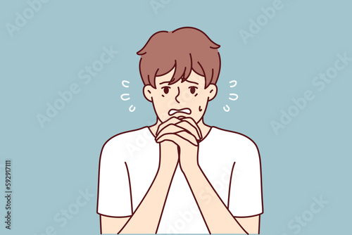 Excited man makes gesture of praying asking lord for help in solving problems that have arisen. Frightened guy praying and begging god to help him recover from disease or be saved for sinful act 