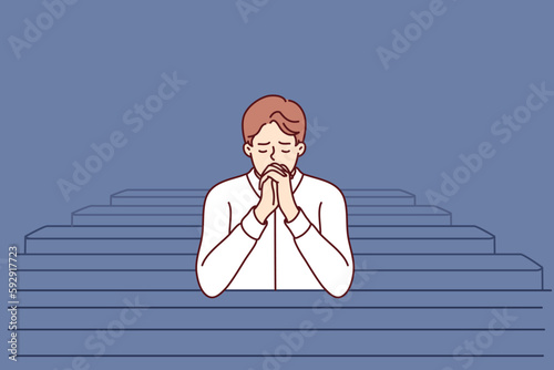 Christian man sits and prays in catholic church, turning to god to confess or ask for help. Believing guy in church and prays to feel psychological relief or observe religious ritual 