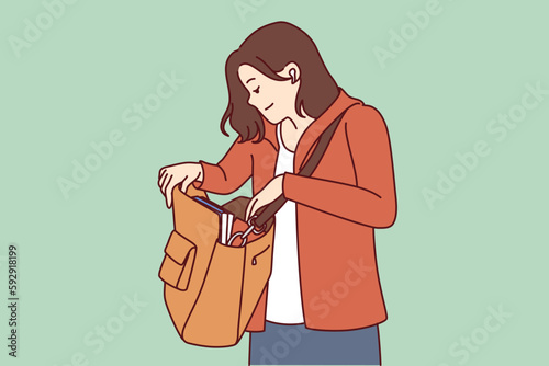 Woman looks into large bag hanging on shoulder in search of wallet or phone lost in handbag. Tourist girl with handbag dressed in casual clothes is trying to find lost or stolen personal items. 