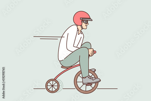 Funny man drives miniature bicycle while rushing to meeting or relaxing in spare time