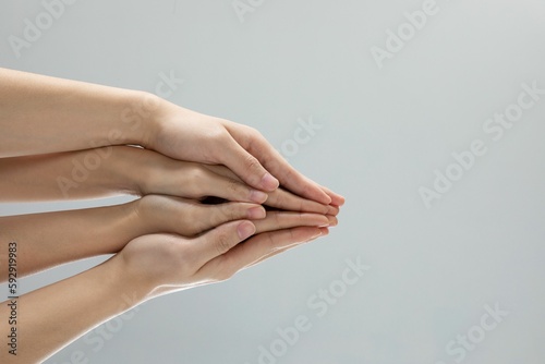 Closeup shot of helping hands touching in front of a gray background