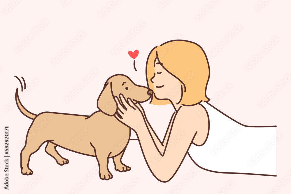 Cute girl kissing puppy enjoying communication with beloved pet and caring for dachshund