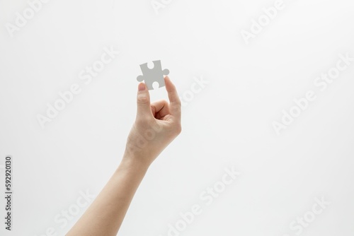 Closeup shot of a hand holding a puzzle piece in front of a white background with copy space