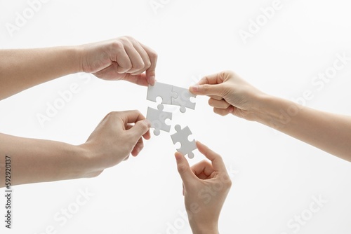 Closeup shot of hands holding puzzle pieces in front of a white background