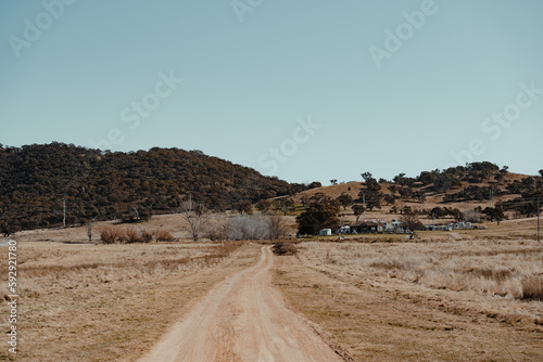 Dirt road driveway leading to a grassy rural property. photo