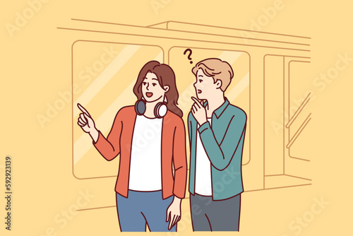 Man and woman are standing near subway or tamway car, choosing shortest path and discussing where to go next. Girl with headphones around neck helps tourist who has lost his way to choose path 