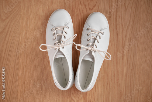 Pair of white gumshoes on wooden background.