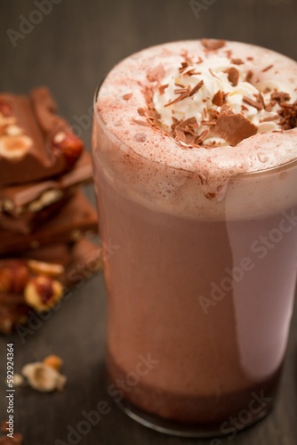 Vertical shot of hot chocolate with cream in a glass cup on a wooden table.