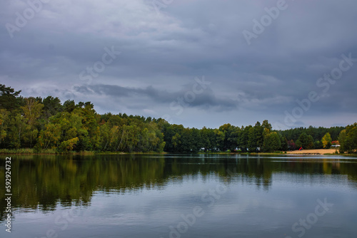 Natural landscape of the lake, high definition, the movement of waves against the background of the autumn forest. The reflection of clouds on the ripples of water. Germany.