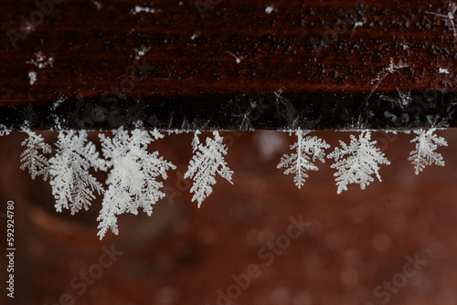 Closeup of snowflakes hanging from a wood outdoors photo