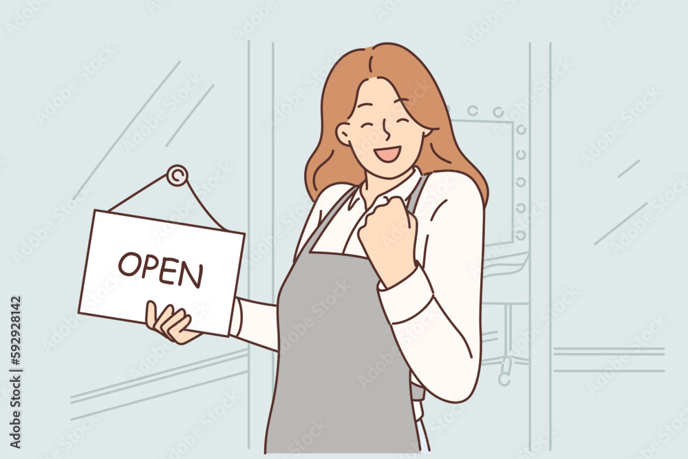 Woman owner of beauty salon makes victory gesture standing near front door with sign open Woman owner of beauty salon makes victory gesture standing near front door with sign open
