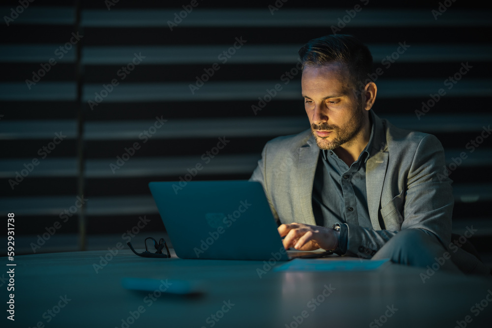 Portrait of a young businessman looking at laptop by night Portrait of a young businessman looking at laptop by night
