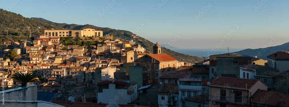 Panoramic shot of a Sicilian village with the sea and mountains in the background on a sunny day