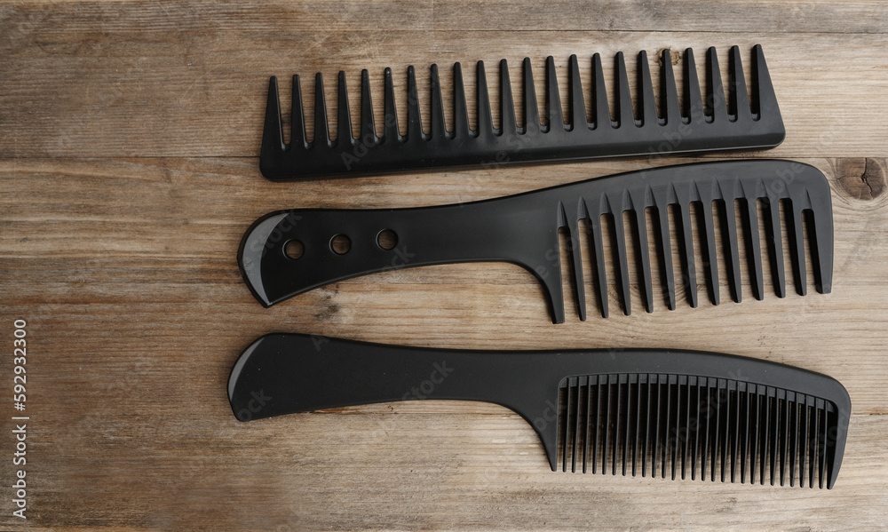 close-up of three black combs with large rare teeth for caring for mustaches and beards lie on old wooden table, concept of mustache and beard stubble care products, hairline hygiene close-up of three black combs with large rare teeth for caring for mustaches and beards lie on old wooden table, concept of mustache and beard stubble care products, hairline hygiene