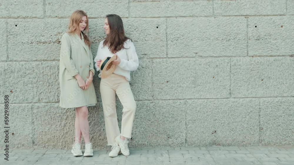 Two young beautiful smiling hipster girls in trendy clothes. Sexy carefree women posing on street background. Positive models 