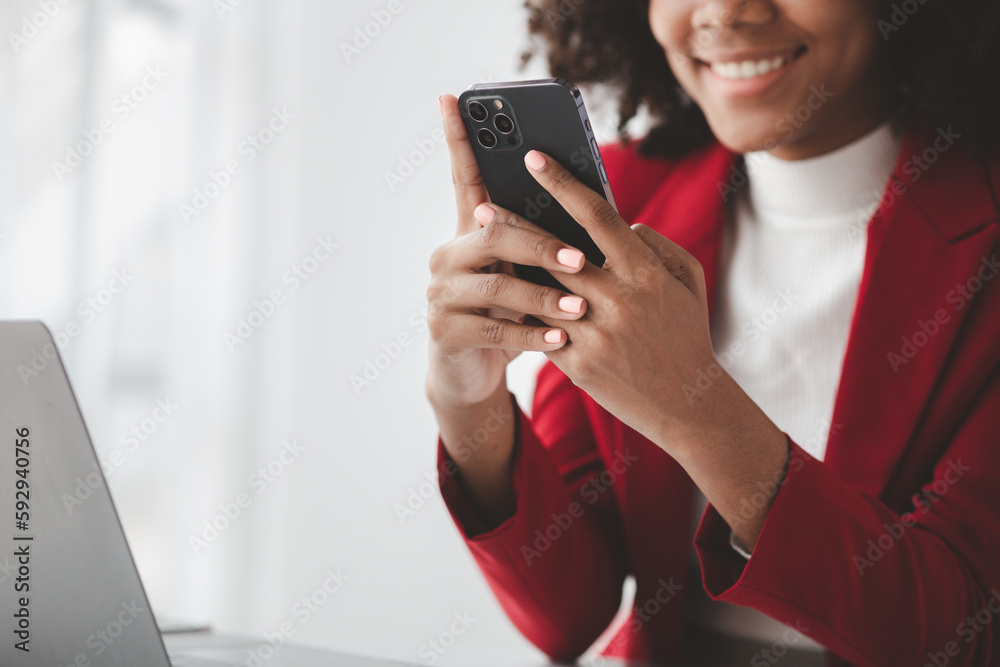 A young American woman is a start-up businesswoman, she sits in the office and uses mobile phones, manages and runs her business from a young generation. Startup business management concept. A young American woman is a start-up businesswoman, she sits in the office and uses mobile phones, manages and runs her business from a young generation. Startup business management concept.