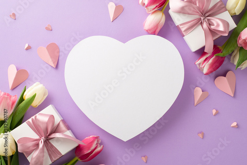 Mother's Day celebration concept. Top view flat lay of pink present boxes with ribbon, tulip flowers, paper hearts on a soft pastel violet background with empty heart for text or advert