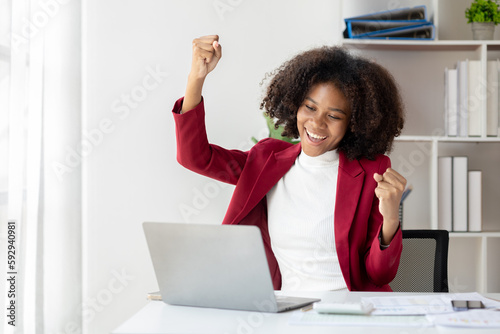 A young American woman is a start-up businesswoman, she sits in the office and looks happy, manages and runs the business from the young generation. Startup business management concept.