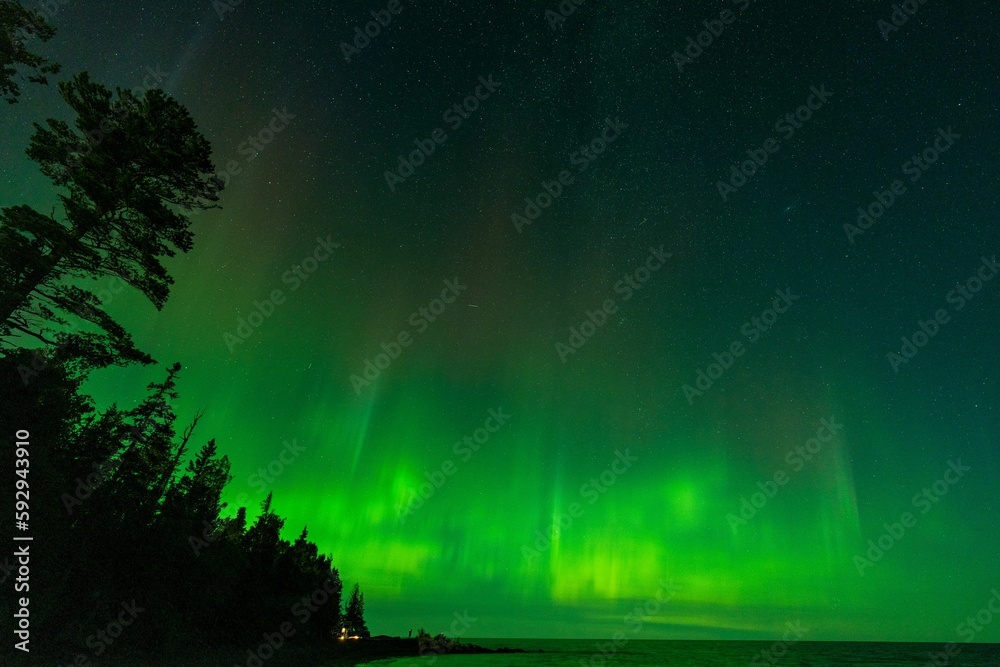 Aurora borealis over the lake surrounded by forest in Keweenaw Peninsula, Michigan