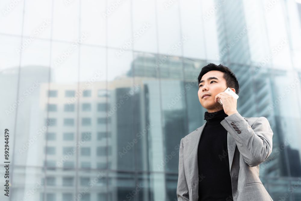 Asian businessman is making a phone call outdoors in the city. Asian businessman is making a phone call outdoors in the city.