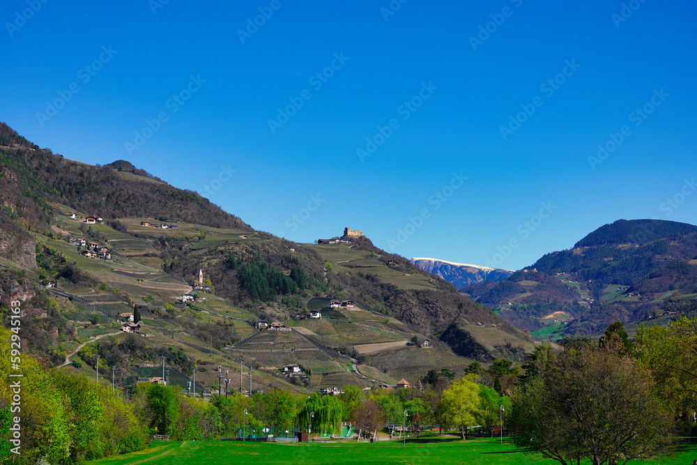 Panoramablick über eine Südtiroler Berglandschaft mit Burgen, Kirchen und Gebäuden am Berghang