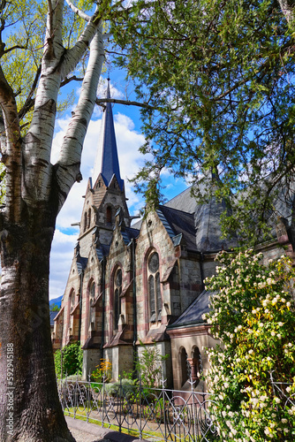 Seitliche Aufnahme der evangelischen Christuskirche in Meran, von der Passerpromenade aus, eingebettet zwischen Bäumen photo