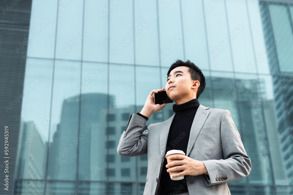 Asian businessman is making a phone call outdoors in the city. Asian businessman is making a phone call outdoors in the city.