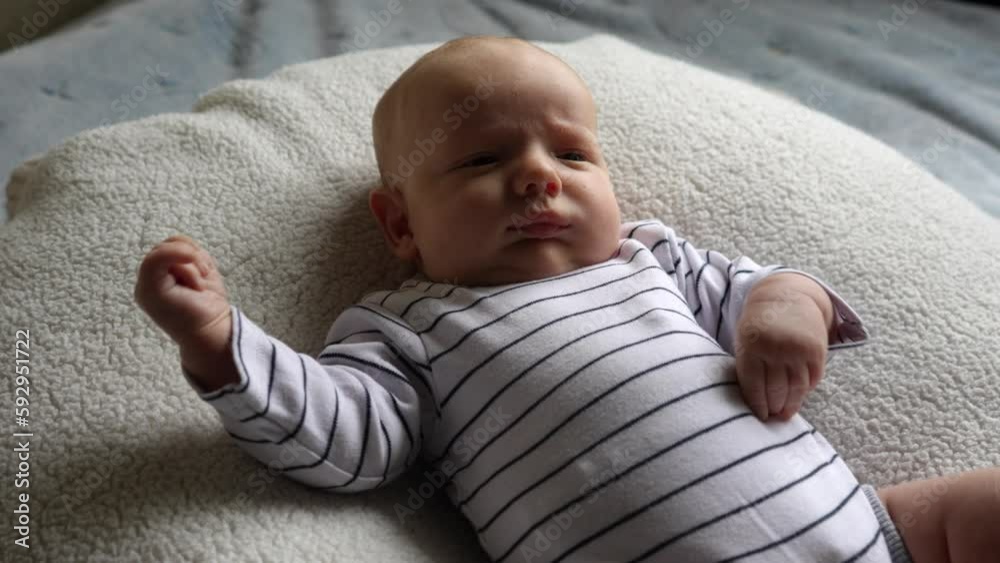 A small child lies on a white blanket and moves his arms, closeup. A