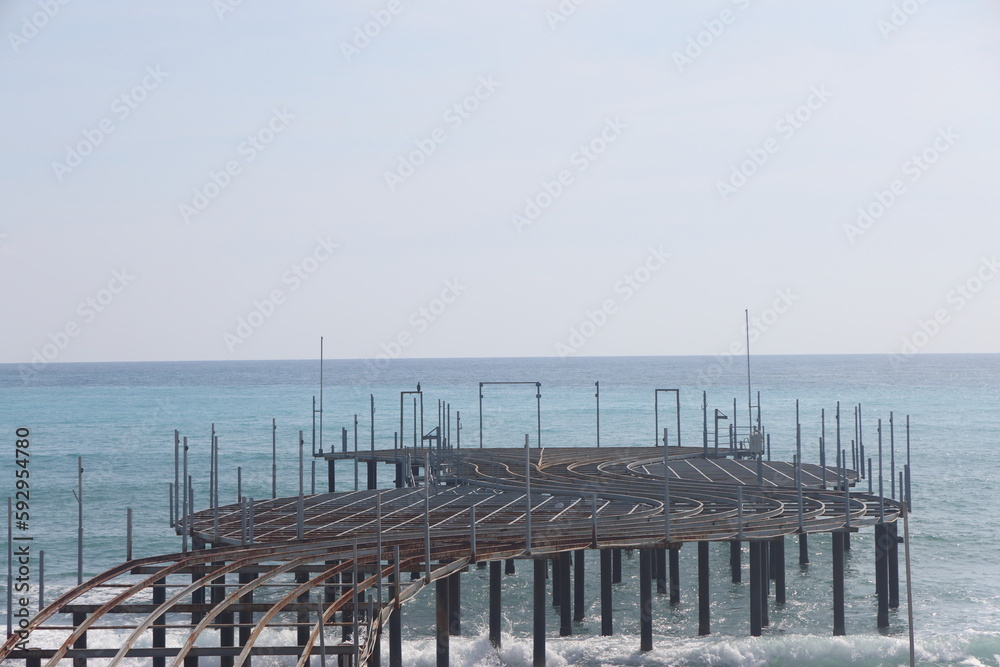Naklejka premium Storm on the sea, waves of foam against the background of the beach pier, Alanya, December 2023.
