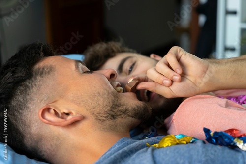 Closeup of a homosexual couple eating chocolate together laying in the bed
