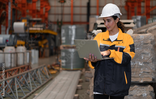 Leinwand Poster Female industrial engineer in white helmet and safety jacket work in heavy metal engineering factory
