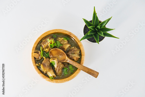 Fresh spicy lamb paya soup in a wooden bowl and ready to eat. Home made mutton soup called paya or attukaal soup in south india. Mutton soup in wooden bowl. Selective focused... photo