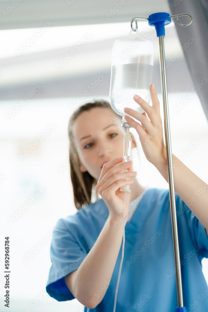 Doctor nurse wear checking saline bag for patient at hospital room. Physician man care drip fluid saline bottle. Health care concept. Doctor nurse wear checking saline bag for patient at hospital room. Physician man care drip fluid saline bottle. Health care concept.