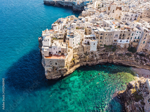 People bathing in the sun in Blue Lagoon, Polignano a Mare the beach. Aerial view of swimming in beautiful clear sea water. Top view from flying drone.