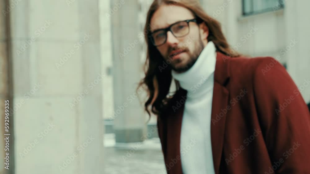 Portrait of attractive bearded hipster man in red fashion coat. Thoughtful and resolute look in big town. Modern businessman model with long hair. Slow motion Portrait of attractive bearded hipster man in red fashion coat. Thoughtful and resolute look in big town. Modern businessman model with long hair. Slow motion