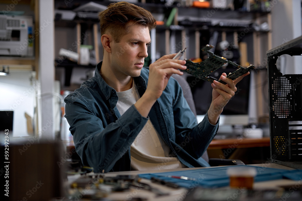 Confident caucasian man disassembles broken laptop. Computer service and repair concept. Laptop disassembling in repair shop, workshop. Electronic development by professional technician Confident caucasian man disassembles broken laptop. Computer service and repair concept. Laptop disassembling in repair shop, workshop. Electronic development by professional technician
