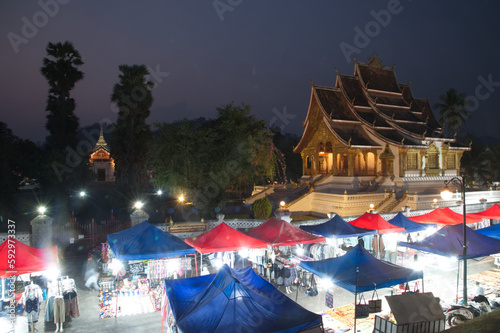 Twilight time at night market is the Haw Pra Bang in the background. It is a famous tourist spot. Popular tourist attraction sell a lot of souvenirs and handicrafts in Luang Prabang city, Laos.