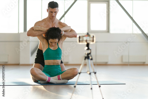 Muscular hispanic man and beautiful girl working out in gym, stretching, blogging, recording video photo