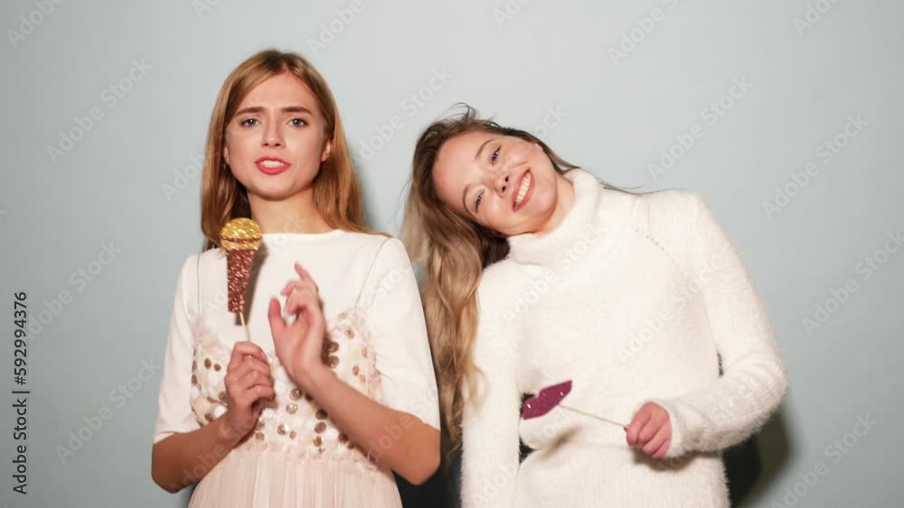 Two young beautiful woman singing with props fake microphone. Trendy girls in casual summer clothes. Positive female emotion facial expression body language with big lips. Funny models isolated Two young beautiful woman singing with props fake microphone. Trendy girls in casual summer clothes. Positive female emotion facial expression body language with big lips. Funny models isolated